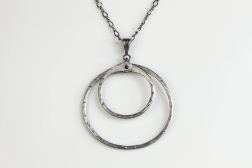 Double Happiness Double Circle Necklace in Hammered Iron. The two handmade, hammered, concentric circles on a sterling silver chain reflect with lovely contrasting iron tones. Together, the Double Happiness iron double Circle Necklace is a simple necklace to wear everyday, or perfect for a fancy night on the town. A perfect iron 6th anniversary gift.