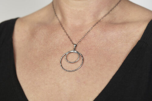 Double Happiness Double Circle Necklace in Hammered Iron. The two handmade, hammered, concentric circles on a sterling silver chain reflect with lovely contrasting iron tones. Together, the Double Happiness iron double Circle Necklace is a simple necklace to wear everyday, or perfect for a fancy night on the town. A perfect iron 6th anniversary gift.