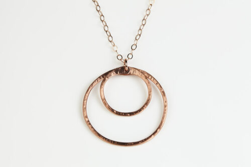 Double Happiness Copper Circle Pendant - two handmade, hammered, concentric circles on a rose gold chain reflecting with a lovely contrasting warm coppery tone on a white background. Copper anniversary gifts for wife