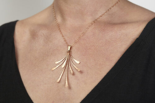 flash - 7th anniversary copper statement necklace being worn. Front view of the delicate chain and 8 slightly curving delicate hammered copper elements reflecting the light. Copper 7th anniversary gifts for wife