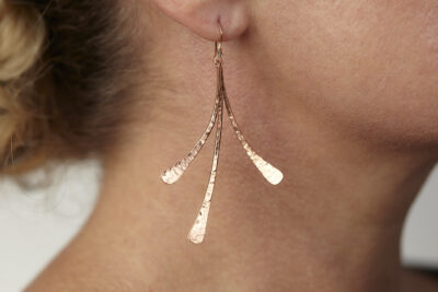 Dirtypretty artwear's Mini Flash Hammered Copper Earrings shown on a model. The three gently curved, hand hammered copper elements shine in the warm light. Copper 7th anniversary gifts for wife