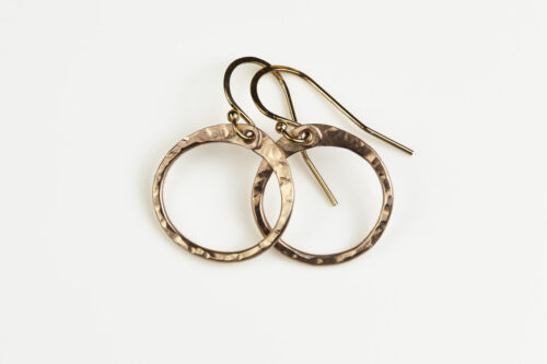 Tiny Zen Circle - Small Hoop Earrings in Bronze displayed nestled together on a white background, these small drop hoop earrings are hand hammered creating a lovely faceted surface that highlights the contrasting light and reflectivity of these simple and beautiful handmade drop hoop earrings. 8th anniversary gifts