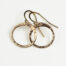 Tiny Zen Circle - Small Hoop Earrings in Bronze displayed nestled together on a white background, these small drop hoop earrings are hand hammered creating a lovely faceted surface that highlights the contrasting light and reflectivity of these simple and beautiful handmade drop hoop earrings. 8th anniversary gifts