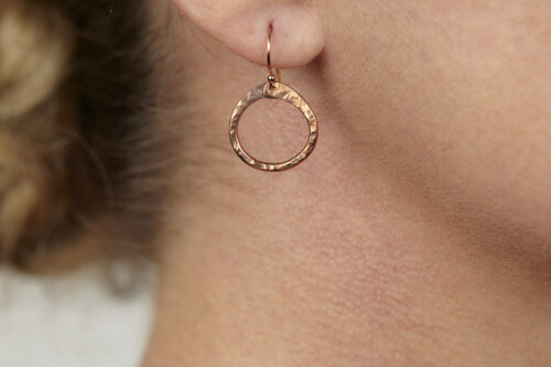 Tiny Zen Circle - Chunky Hoop Earrings in Copper. A closeup shown wornd, these small drop hoop earrings are hand hammered creating a lovely faceted surface that highlights the contrasting light and reflectivity of these simple and beautiful handmade drop hoop earrings. Copper gifts for her