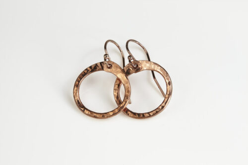 Tiny Zen Circle - Chunky Hoop Earrings in Copper displayed nestled together on a white background, these small drop hoop earrings are hand hammered creating a lovely faceted surface that highlights the contrasting light and reflectivity of these simple and beautiful handmade drop hoop earrings. Copper anniversary gifts for her