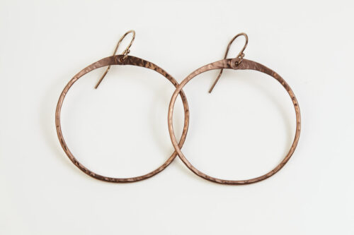 The Zen Circle - Copper Large Hoop Earrings. Displayed hanging on a white background, Feature simple hammered copper circles embodying the Japanese concept of Enso, the Zen Circle - Copper Large hoop earrings are beautifully understated yet striking earrings. The hammered copper reflects the warm light in facets creating a lovely and simple everyday earrings. The rose gold fill ear wires matches the warm tones of the copper perfectly. Small and light enough for every day, but sophisticated enough for a fancy night out, The Zen Circle - Copper Large Hoop Earrings are a perfect gift for any occasion. Copper anniversary gifts for her