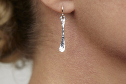 Simple Chic - Aluminum Bar earrings displayed laying on a white background. The uniquely minimalist aluminum bar dangle earrings display their uniquely hammered textures in the warm light. Sterling silver ear wires match the aluminum. These rustic and simple earrings are perfect for everyday wear, or are elegant enough for a fancy night out.