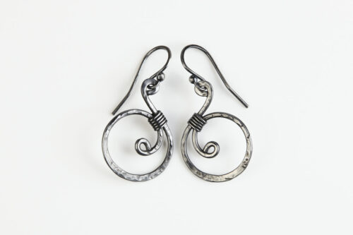 The Tiny Swirls - Spiral Hoop Earrings in Iron. These iron drop hoop spiral earrings have a wire wrapped iron detail that creates the closed circle of the hoop creating a tiny spiral inside the hoops that provide the cute focal point of the earrings. Delicately hammered facets reflect the light of the hammered iron. The sterling silver ear wires match the polished iron perfectly. Small and light enough for every day, but sophisticated enough for a fancy night out, the Tiny Swirls - Spiral Hoop Earrings in iron are perfect for every occasion and make a lovely 6th anniversary gift for her