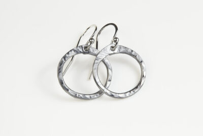 Tiny Zen Circle - Aluminum Tiny Hoop Earrings displayed nestled together on a white background, these small drop hoop earrings are hand hammered creating a lovely faceted surface that highlights the contrasting light and reflectivity of these simple and beautiful handmade Aluminum Tiny Hoop Earrings