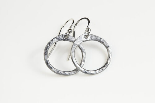 Tiny Zen Circle - Aluminum Tiny Hoop Earrings displayed nestled together on a white background, these small drop hoop earrings are hand hammered creating a lovely faceted surface that highlights the contrasting light and reflectivity of these simple and beautiful handmade Aluminum Tiny Hoop Earrings