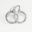Tiny Zen Circle - Aluminum Tiny Hoop Earrings displayed nestled together on a white background, these small drop hoop earrings are hand hammered creating a lovely faceted surface that highlights the contrasting light and reflectivity of these simple and beautiful handmade Aluminum Tiny Hoop Earrings