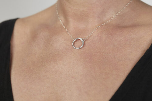 The Tiny Zen Circle - Aluminum Simple Circle Necklace. Shown on a white background, a simple hammered Aluminum circle embodying the Japanese concept of Enso, the Tiny Zen Circle - Aluminum Simple Circle Necklace a beautifully understated yet striking minimalist necklace. The hammered Aluminum reflects the cool light in facets creating a lovely and simple everyday necklace. The sterling silver chain matches the aluminum perfectly. Small and light enough for every day, but sophisticated enough for a fancy night out, The Tiny Zen Circle - Aluminum Simple Circle Necklace is a perfect gift for every occasion and makes a lovely Aluminum anniversary gift for her