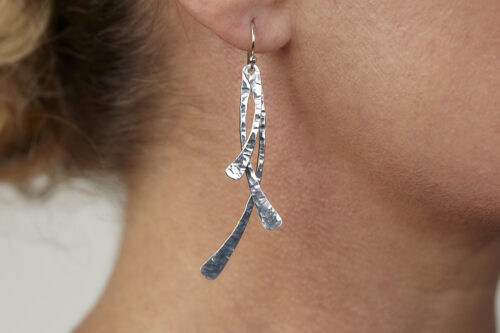 Trio Aluminum Boho Earrings displayed laying on a white background. The three delicately curved and hammered aluminum dangles reflect the light in facets. The sterling silver ear wires match the cool tones of the aluminum perfectly. Small and light enough for every day, but sophisticated enough for a fancy night out, the Trio Aluminum Boho Earrings are perfect for every occasion.
