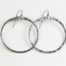 The Zen Circle - Aluminum Large Hoop Earrings. Displayed on a white background, Feature simple hammered Aluminum circles embodying the Japanese concept of Enso, the Zen Circle - Aluminum hammered hoop earrings are beautifully understated yet striking earrings. The hammered Aluminum reflects the cool light in facets creating lovely and simple everyday earrings. The sterling silver ear wires match the warm tones of the Aluminum perfectly. Small and light enough for every day, but sophisticated enough for a fancy night out, The Zen Circle - Aluminum Large Hoop Earrings are a perfect gift for any occasion.