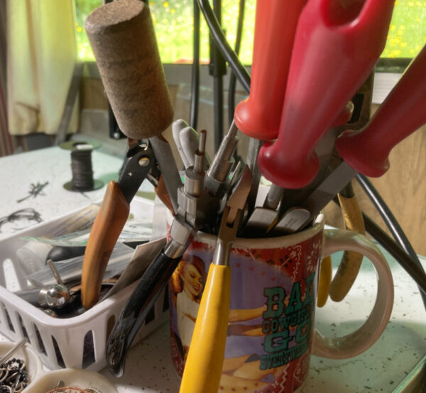 a cluttered work bench with lots of jewelry files, cutters and pliers
