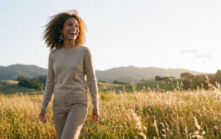 a model wearing mini flash earrings in Iron strolls through a field with a smile. A perfect 6th anniversary gift for her