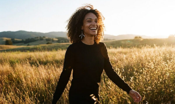 a model wearing mini flash earrings in Iron walking in a field with a smile. A perfect 6th anniversary gift for her