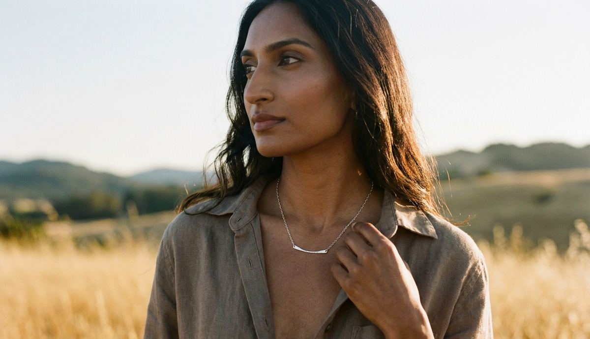a woman enjoying the golden hour is wearing her 10th anniversary gift of a simple chic aluminum bar necklace for her aluminum anniversary