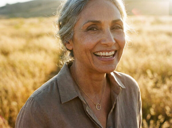 a woman is enjoying the golden hour while she celebrates her gold anniversary with a tiny zen circle necklace on her 50th anniversary